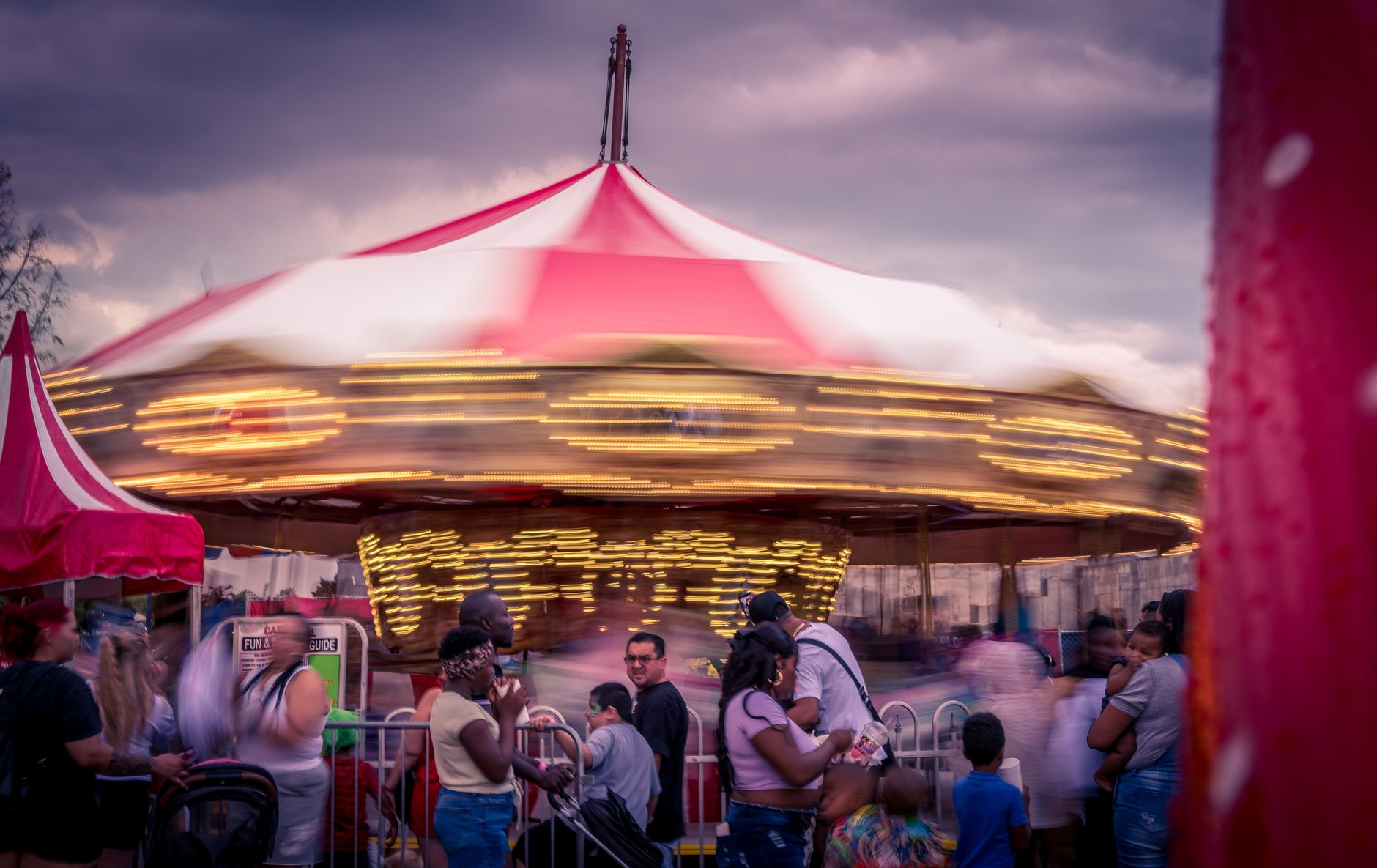 Buntes Karussell auf einem Jahrmarkt im Abendlicht, umgeben von Besuchern